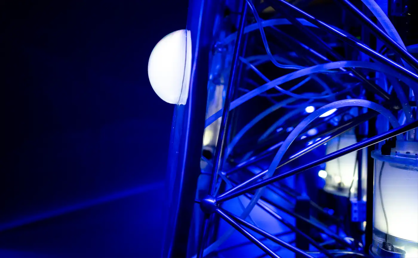 The steel frame and tubing behind the sculpture, with a glowing bubble on its surface